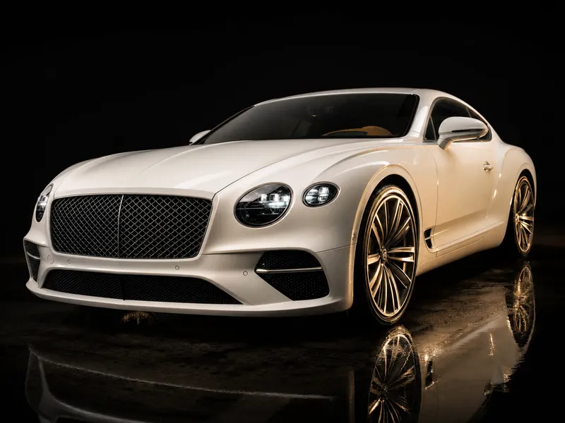 Pearl-white luxury grand tourer finished to showroom perfection in a dark studio